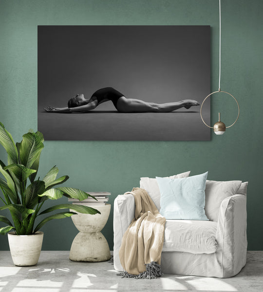 Artwork on the living room green wall, giving a chill and meditative vibe. Print image of a ballerina, stretching on the floor, body arch, breathing. Photo print studio, colors black and white