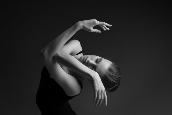 Dancer, female, portrait, close-up. Intertwined hands, in front of the face, eyes closed. head is on the side. she is dancing.