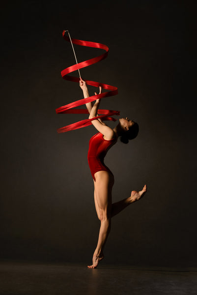 Female gymnast, red bodysuit, practicing, ribbon, red.